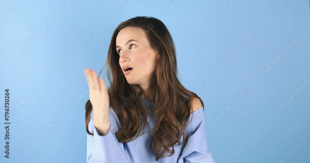 Displeased young woman wearing blue pullover is looking to the nail, yawn, look at side while look bored, shake her head isolated over blue background. Displeased young woman wearing blue pullover is looking to the nail, yawn, look at side while look bored, shake her head isolated over blue background.