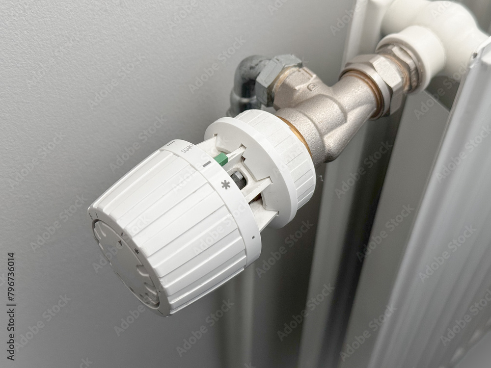Woman Hand Adjusting The Knob Of Heating Radiator. The valve from the radiator - Heating. Hand adjusting thermostat valve of heating radiator in a room. Copy space. Woman Hand Adjusting The Knob Of Heating Radiator. The valve from the radiator - Heating. Hand adjusting thermostat valve of heating radiator in a room. Copy space.