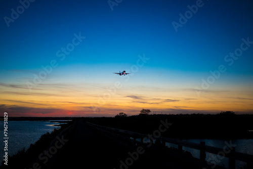 Airplane in silhouette approaching the airport of Faro, over Ria Formosa natural park during sunset