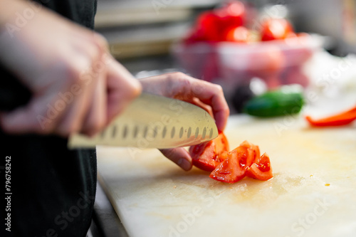 Chef skillfully slicing fresh red tomatoes on a cutting board in a kitchen, highlighting culinary technique and freshness