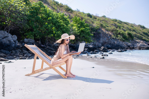 Happy sexy freelance woman wearing bikini sunglasses workout relaxed  with work on laptop computer at beach in summer holidays