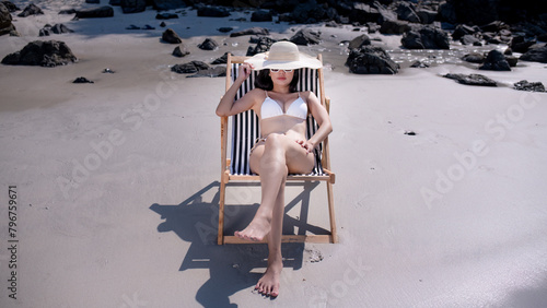 Happiness sexy woman wearing bikini ,hat beach siting beach relaxed and happy on holiday vacation have lotion sun skin and earphone for listen music is summer holidays concept