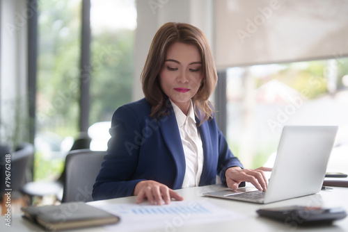 Asian businesswomen reading marketing business report to checking financial chart data and typing data on keyboard laptop while analyze investment and market stock of new startup in outside office
