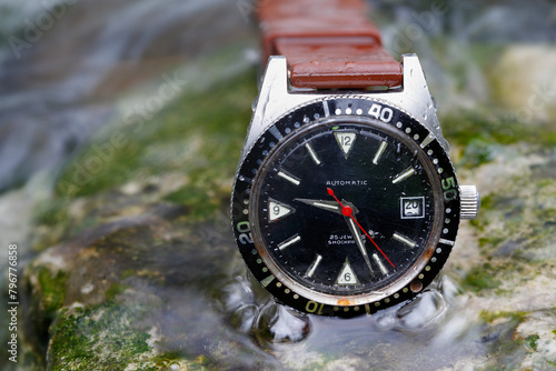 A robust, old mechanical watch defies the elements in the stream, reliable and indestructible. Time, nature, and technology in harmonious unity.
