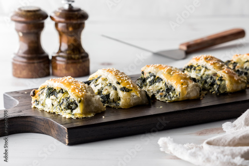 A wooden board topped with homemade spinach and feta pastry appetizers.