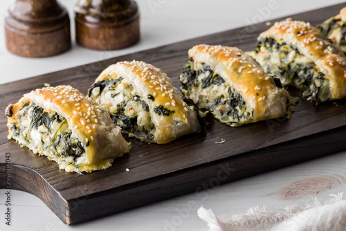 Spinach and feta pastry appetizers on a wooden board, ready for sharing.