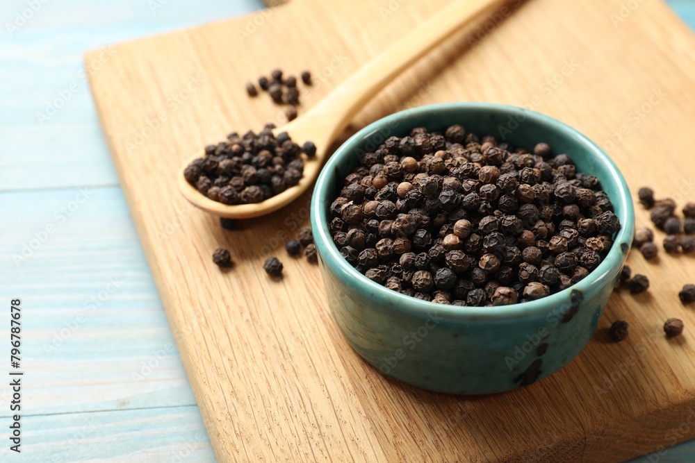 Aromatic spice. Black pepper in bowl on light blue wooden table, closeup Aromatic spice. Black pepper in bowl on light blue wooden table, closeup