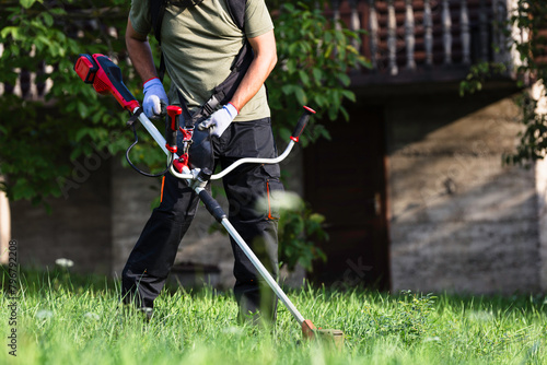 Man mowing grass with a string trimmer © zphoto83