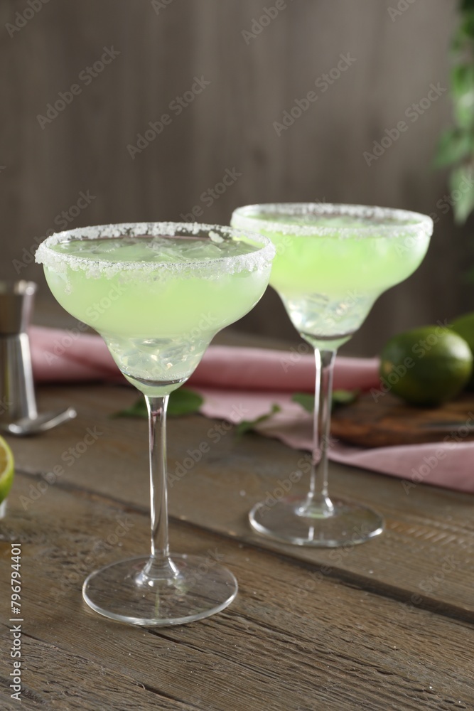 Delicious Margarita cocktail in glasses on wooden table, closeup