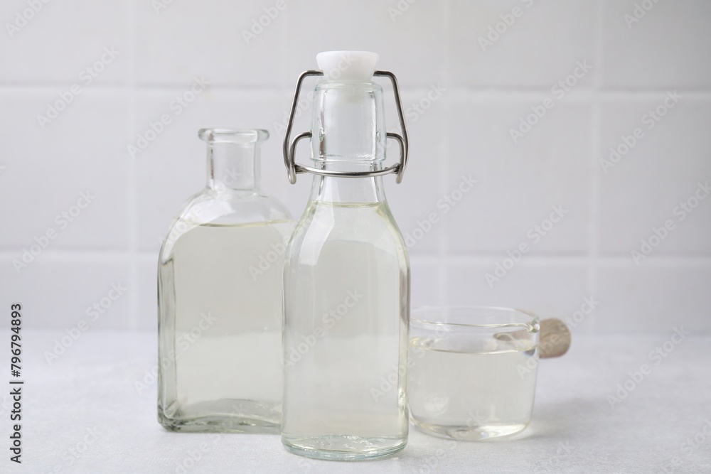 Vinegar in glass bottles and saucepan on light table Vinegar in glass bottles and saucepan on light table