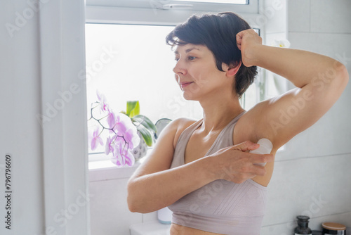 Photos Young woman applying natural crystal alum deodorant in light modern bathroom