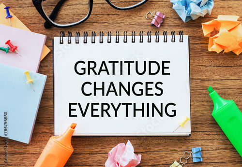 A notepad with the phrase GRATITUDE CHANGES EVERYTHING amidst colorful markers, glasses, and paper.