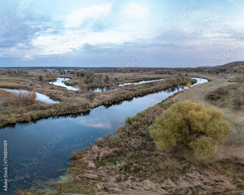 Aerial river curve panorama with trees growing on riverside with cloudy sky in Ukraine