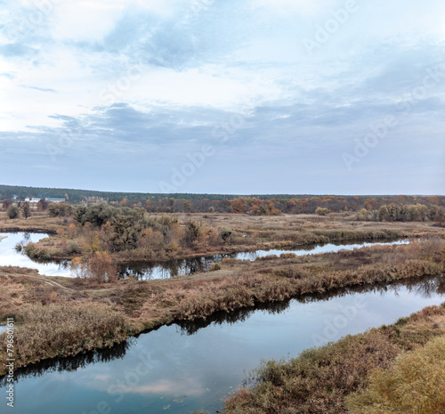 Autumn river valley landscape with bare trees and cloudy sky in Ukraine countryside