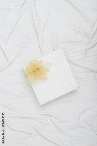 White gift box on crumpled bed sheets mockup