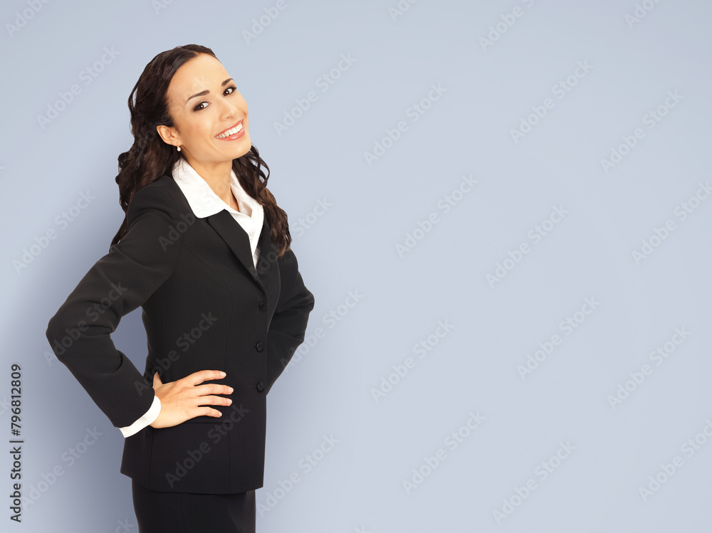 Happy excited smiling businesswoman, with blank space area for ad slogan or advertise text. Confident brunette woman wear black suit isolated grey gray studio wall background. Business ad concept. Happy excited smiling businesswoman, with blank space area for ad slogan or advertise text. Confident brunette woman wear black suit isolated grey gray studio wall background. Business ad concept.