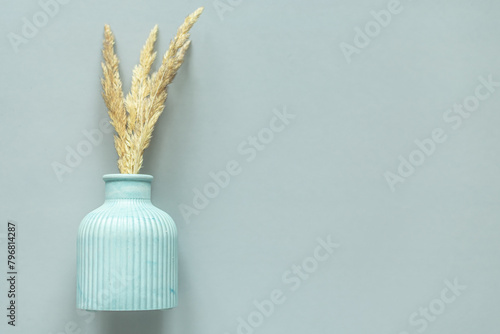 flatley plaster vase with dried flowers on a plain gray background. free space for text