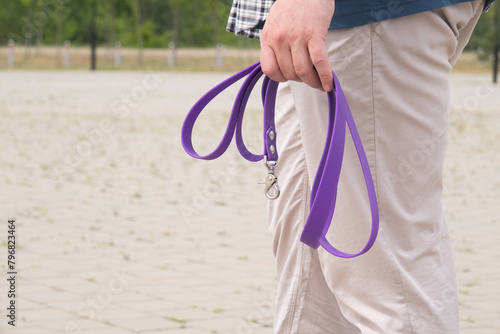 man walking his dog in the park in the morning, man holding purple dog leash