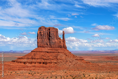 Arizona's Monument Valley East Mitten during a bright and partly cloudy day shows its beauty as it rests in a desert environment. photo