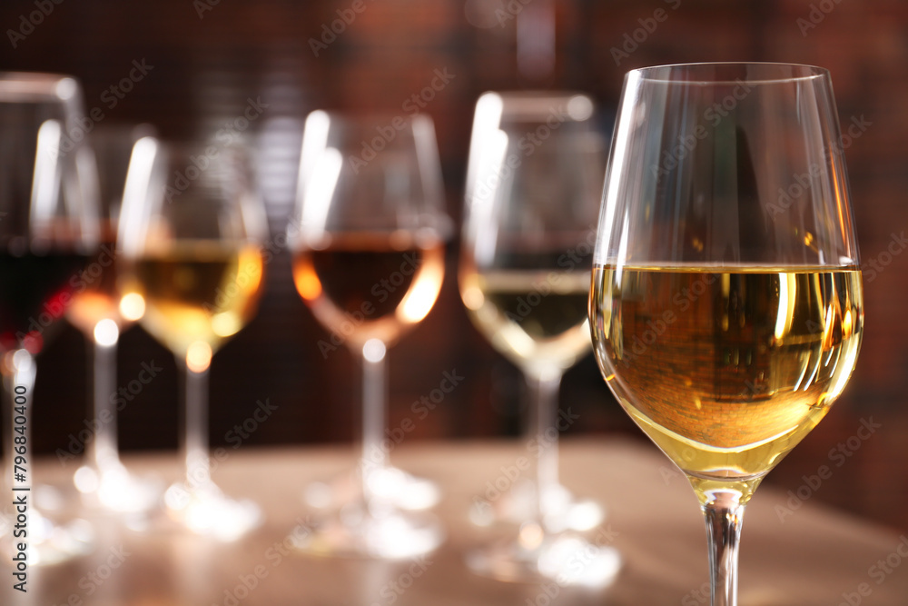 Tasty white wine in glass against blurred background, space for text Tasty white wine in glass against blurred background, space for text
