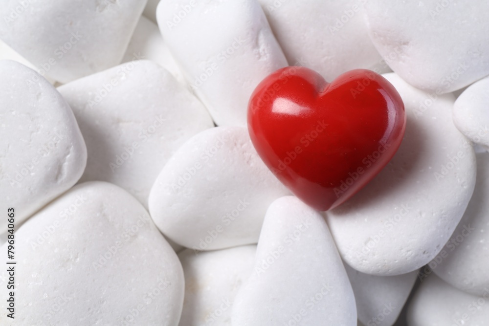 Obraz premium Decorative heart on white pebble stones, top view