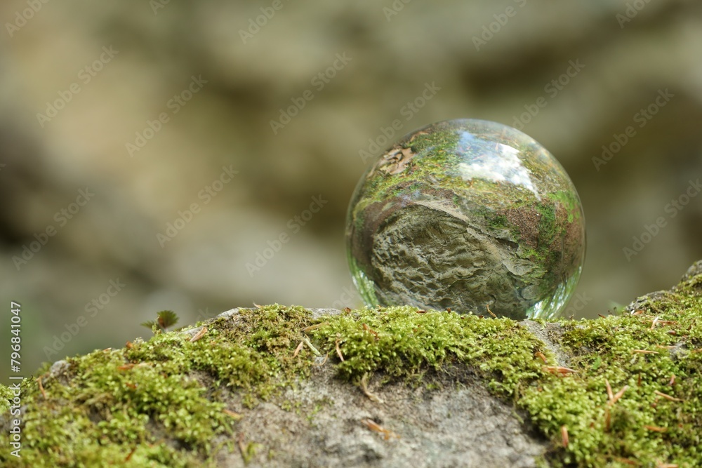 Beautiful forest, overturned reflection. Crystal ball on stone surface with moss outdoors. Space for text Beautiful forest, overturned reflection. Crystal ball on stone surface with moss outdoors. Space for text