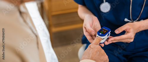 Young woman putting digital oximeter of finger middle aged adult patient for measurement, nurse checking with fingertip pulse oximeter oxygen meter blood monitor finger of senior old man at hospital photo