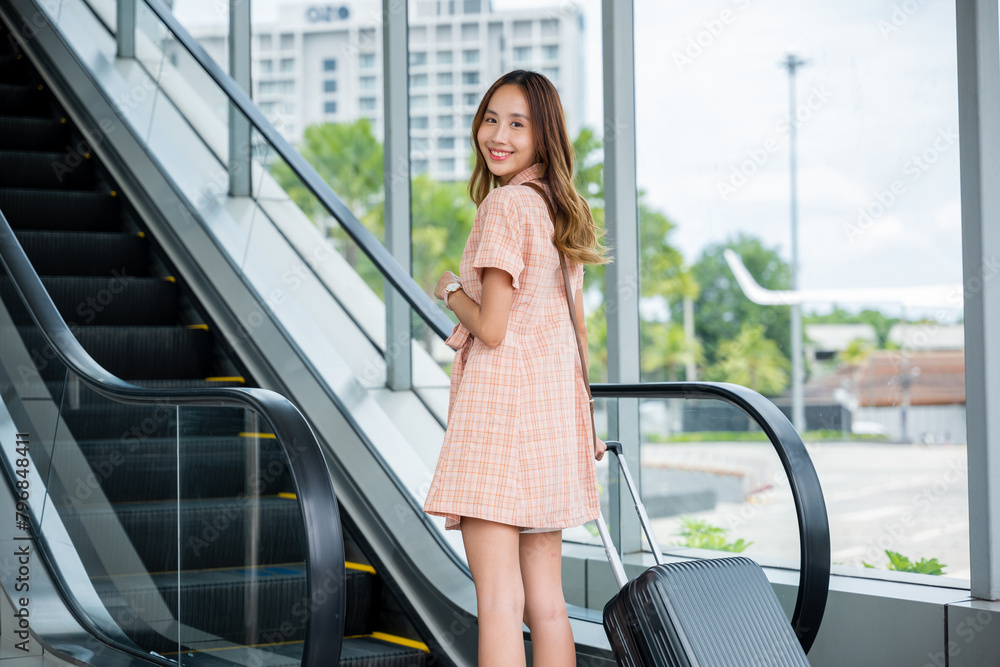 Φωτογραφία Woman carries her luggage up an escalator in modern airport terminal, surrounded by the hustle and bustle of travel