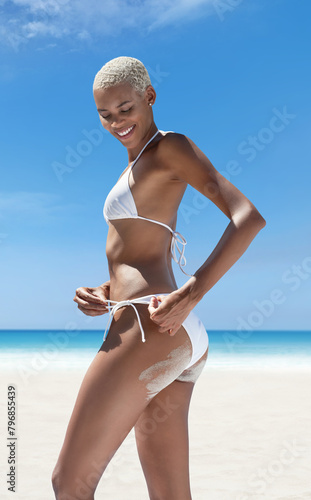 Hot summer holiday, woman on the beach wearing a bikini with sand on her buttocks. Against the panoramic seaside background. Concept of online shopping, skincare protection, travel and resort booking