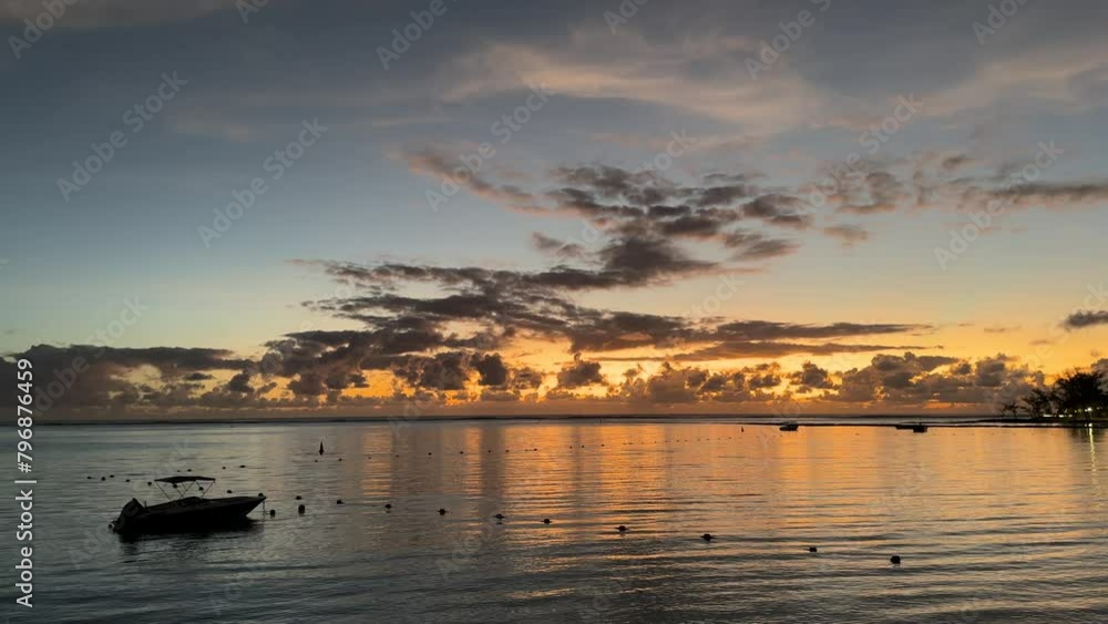 The beautiful yellow sunset on the island of Mauritius in summer with numerous clouds and great weather. In the foreground you can see the sea with a small ship. The beautiful yellow sunset on the island of Mauritius in summer with numerous clouds and great weather. In the foreground you can see the sea with a small ship.
