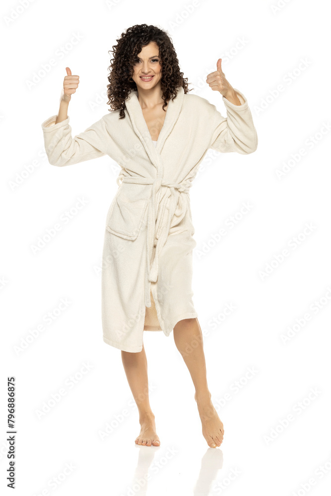 young happy woman posing in bathrobe and showing thumbs up on a white background young happy woman posing in bathrobe and showing thumbs up on a white background
