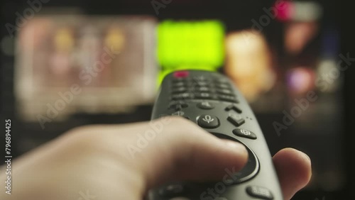 Woman with remote in hand switching channels, smart tv technology internet video content, screen with media content at the background close up shot.