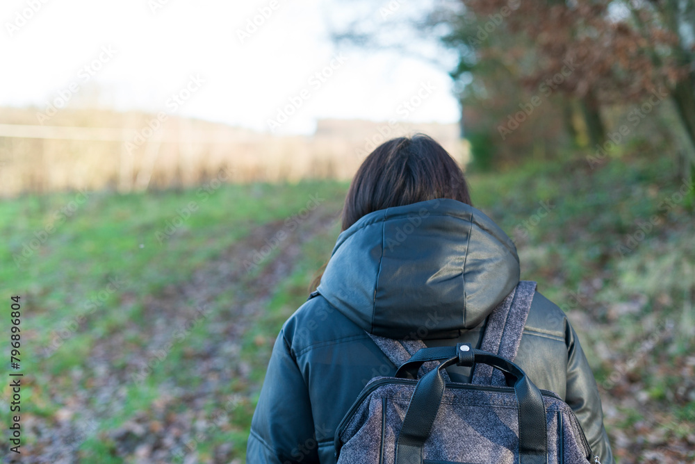 Back view of a young woman with backpack walking in the countryside. Back view of a young woman with backpack walking in the countryside.