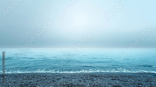   A large body of water rests atop a sandy shore, its edge lapped by gentle waves that consistently ebb and flow photo