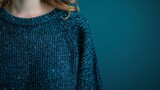   A woman wears a blue sweater with sequins at the back, as depicted in this close-up image