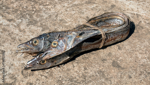 asian ribbon fish or hairtail on rugh background. Dried sea fish from bay of bangle. also called Churi Shutki. popular in chattogram, Bangladesh. looks like knife and it has shiny silver color. photo