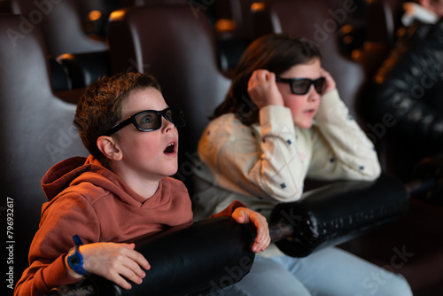 Excited kids wearing 3D glasses in movie theater photo