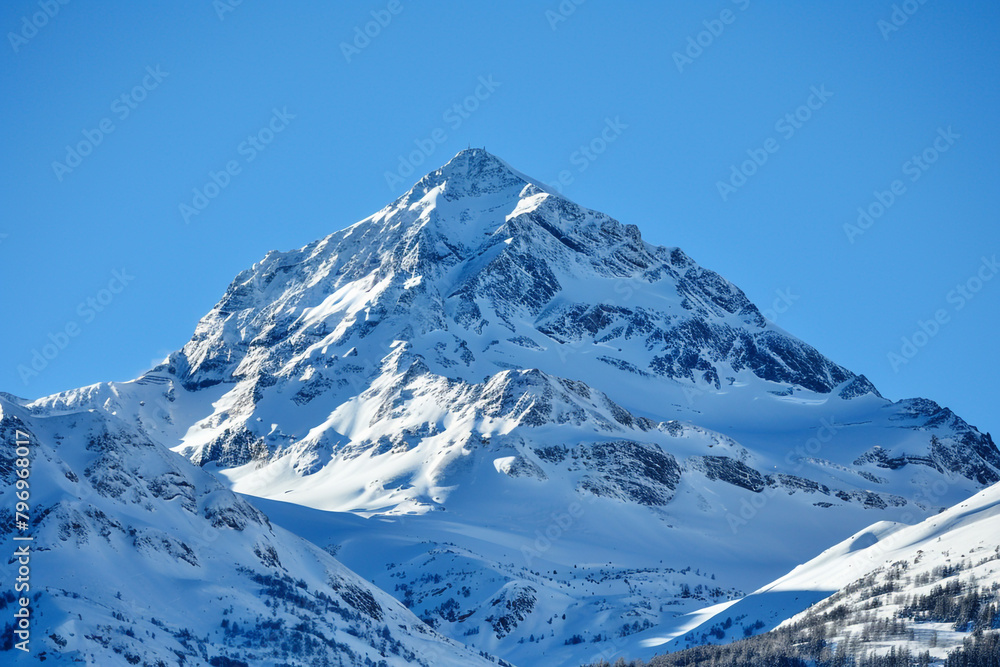 A mountain peak covered in a blanket of snow against a clear blue sky