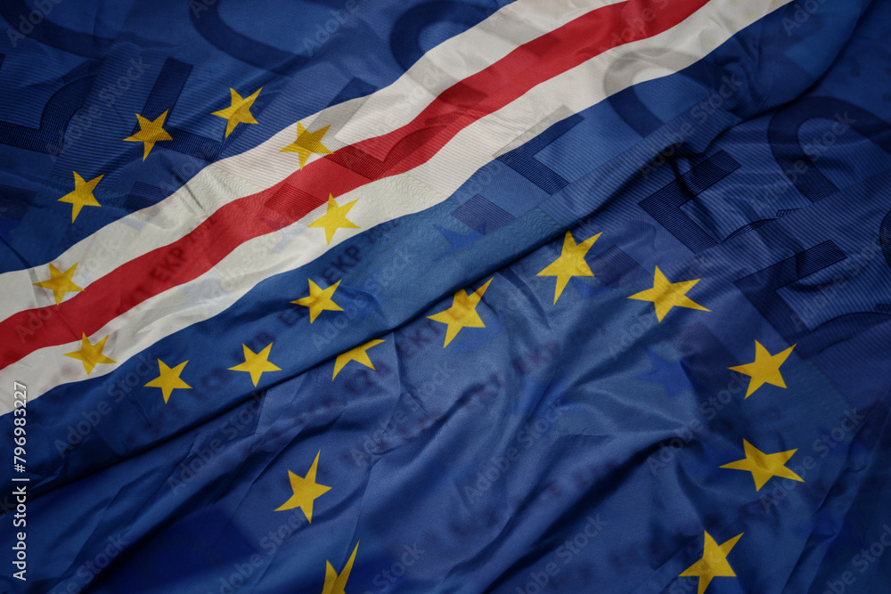 waving colorful flag of european union and flag of cape verde on a euro money banknotes background. finance concept. waving colorful flag of european union and flag of cape verde on a euro money banknotes background. finance concept.
