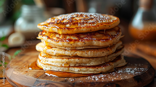 A stack of pancakes with bananas and raspberries on top. The pancakes are covered in syrup and the raspberries are scattered around the plate. The plate is placed on a wooden table photo