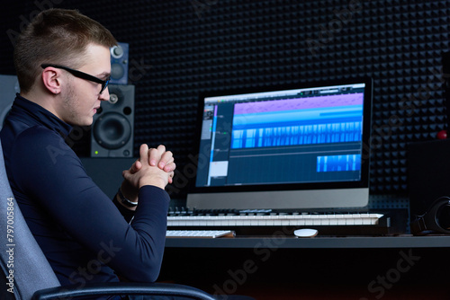 Thoughtful sound engineer focusing on track while working on computer in studio