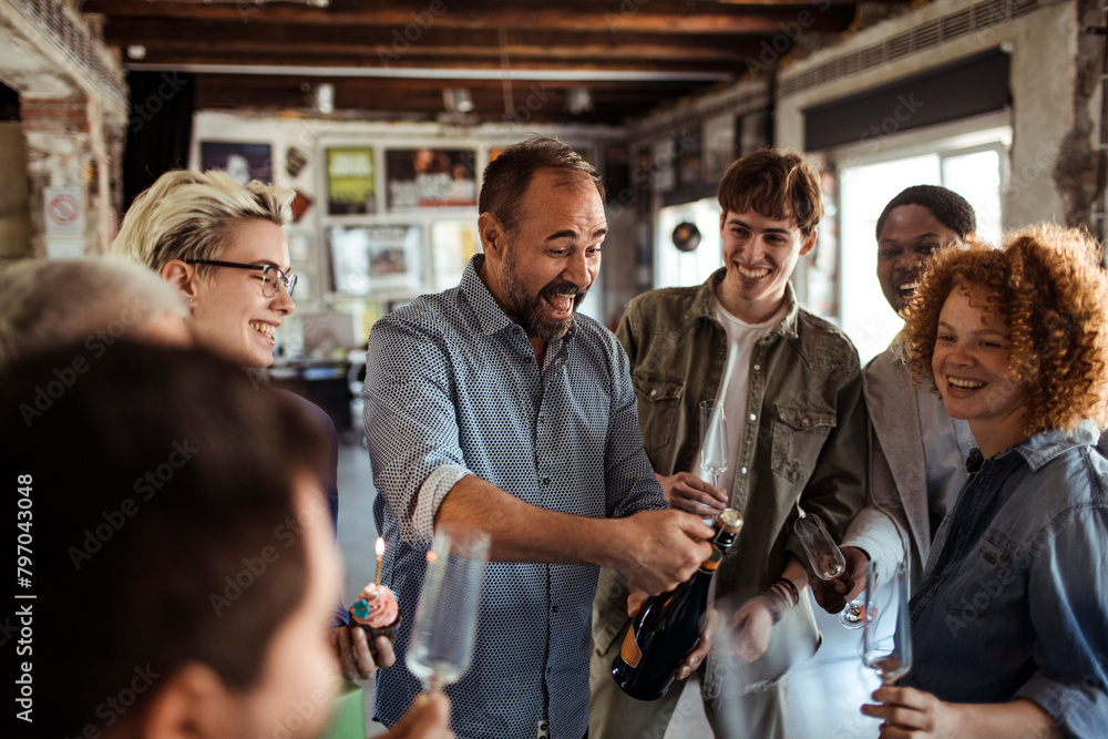 © Davor - Multigenerational and diverse group of people celebrating a birthday in a startup company office