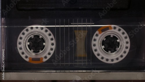 A tape recorder is playing an audio cassette. Close-up. A vintage audio cassette spins on a blank label tape used to record sound in a retro cassette player. Recording of conversations.
