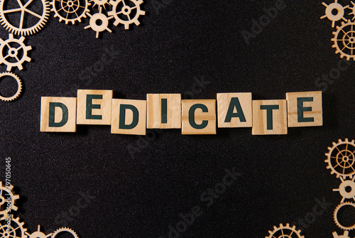 Word Dedicate on a row of wooden blocks. Devotion dedication love concept. photo