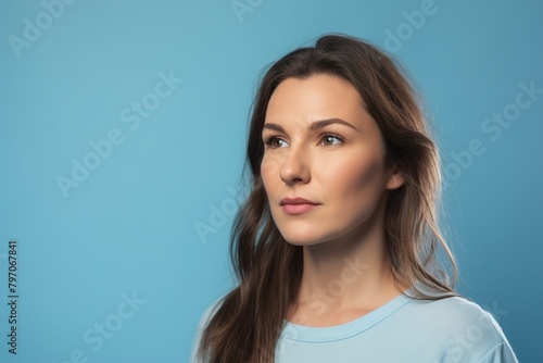 A woman with long hair and a blue shirt is looking at the camera