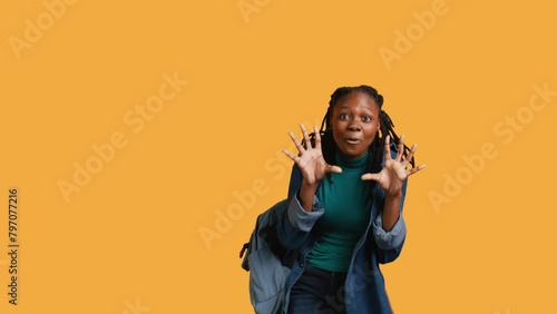 Upbeat african american teenager goofing around, feeling joyous, isolated over studio background. Portrait of happy young girl acting silly, showing positive demeanor, camera B photo