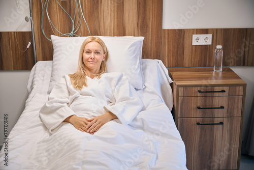 Hospitalized smiling female lying in hospital bed