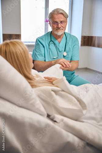 Male doctor supporting lady patient on hospital bed © Viacheslav Yakobchuk