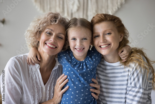 Portrait of multi-generational women, adorable preschooler 5s girl her young 30s mum and middle-aged 55s granny posing for camera. Motherhood, Happy Mothers Day celebration, family ties and attachment