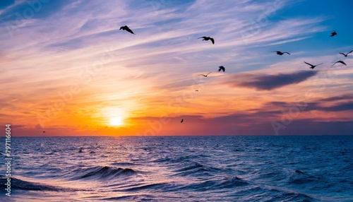 beautiful sunset with purple clouds and flying birds over the sea © Heaven